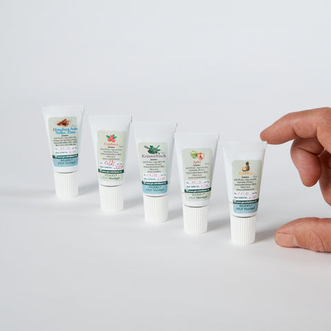 Fünf Mundgelproben in einer Reihe. Daumen und Zeigefinger verdeutlichen die Größe.