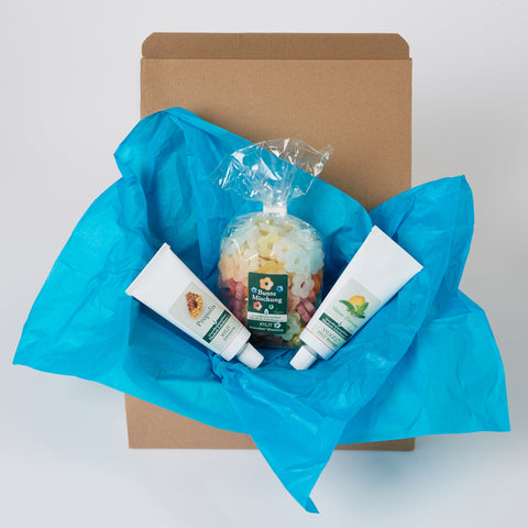 Ein Versandkarton mit blauem Papier ausgelegt, darin befindet sich eine 75g Tube Propolis Zahnpasta eine 500g Packung XYLIT-BLÜMCHEN Bunte Mischung und eine 75g Tube Xyligel Minze-Zitrone